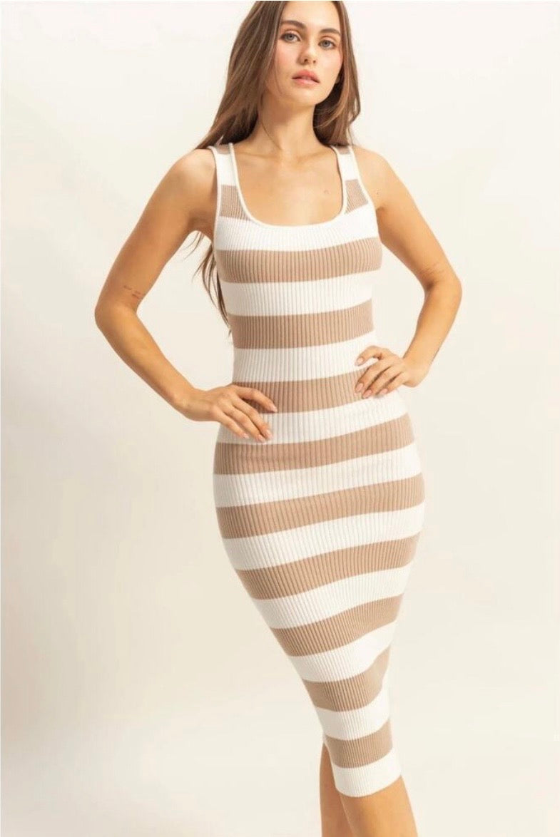 A woman modeling a fitted ribbed knit midi dress with horizontal beige and white stripes against a plain light background.